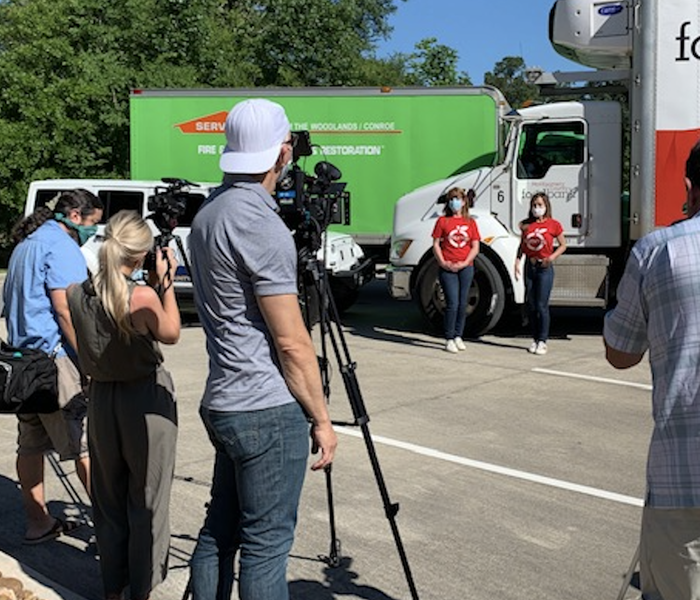 people standing in front of a white and red truck and a SERVPRO truck