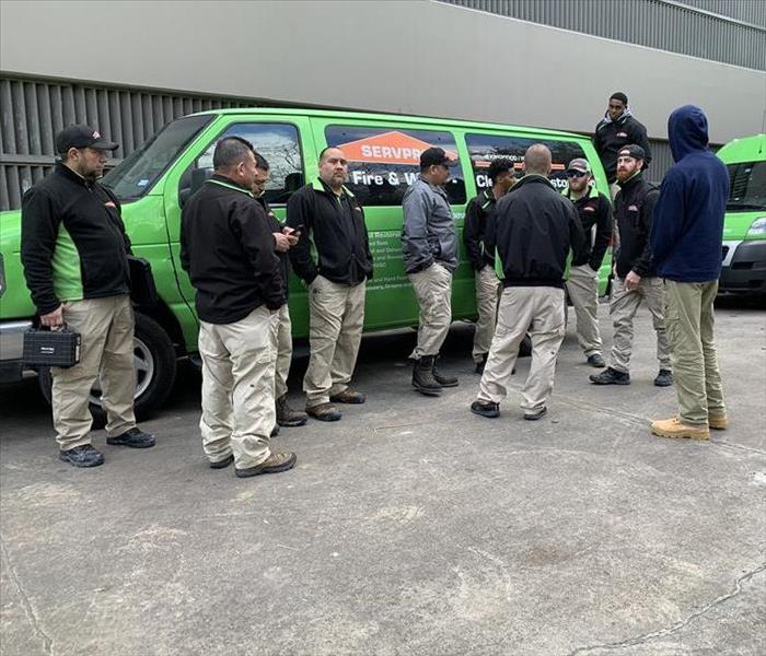 Water damage crew stands in front of a SERVPRO van